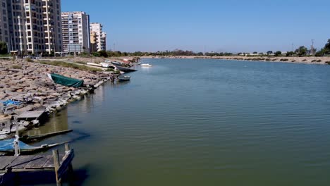 El-Río-Segura-Fluye-Hacia-El-Océano-En-La-Costa-De-España-Con-Barcos-Viejos-Y-Hundidos-A-Lo-Largo-De-La-Costa-Por-Edificios-De-Apartamentos