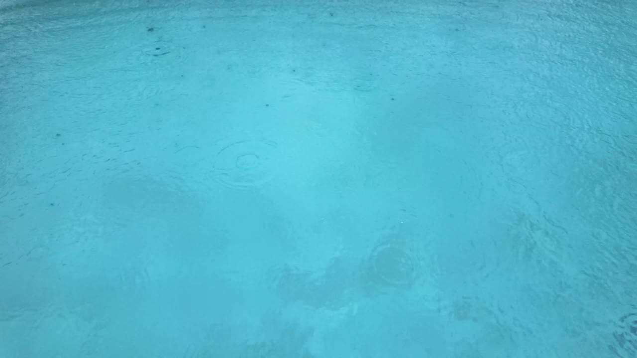 Raindrops drops over swimming pool water surface clean clear bad weather