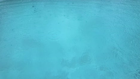 raindrops drops over swimming pool water surface clean clear bad weather