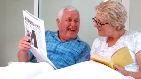 smiling senior couple reading newspaper