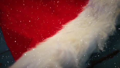 video composition with falling snow over desk with santas hat