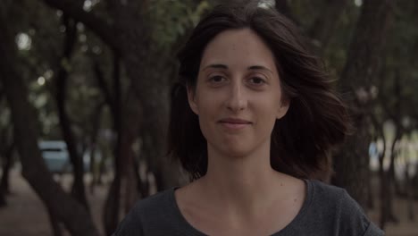 Girl-smiling-in-olive-forest-on-windy-day,-close-up,-slow-motion