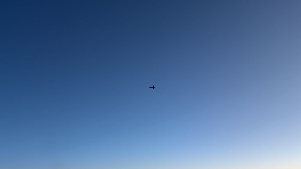 An aerial view from inside a jet cockpit of an aerial jet crossing while flying at sunset at high altitude.
