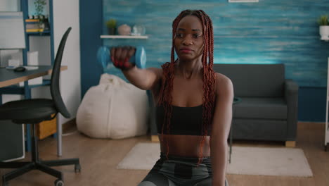 athletic black woman exercising body exercises with yoga dumbbells