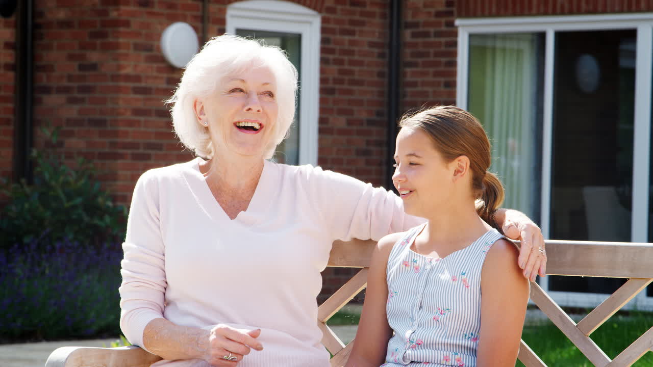 손녀 가 노인 집 을 방문 하는 동안 할머니 와 함께 벤치 에 앉아 있다