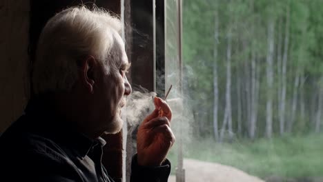 senior man smoking by window