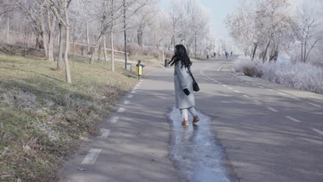 Mujer-Deslizándose-Por-El-Charco-Congelado-En-La-Carretera-En-Invierno