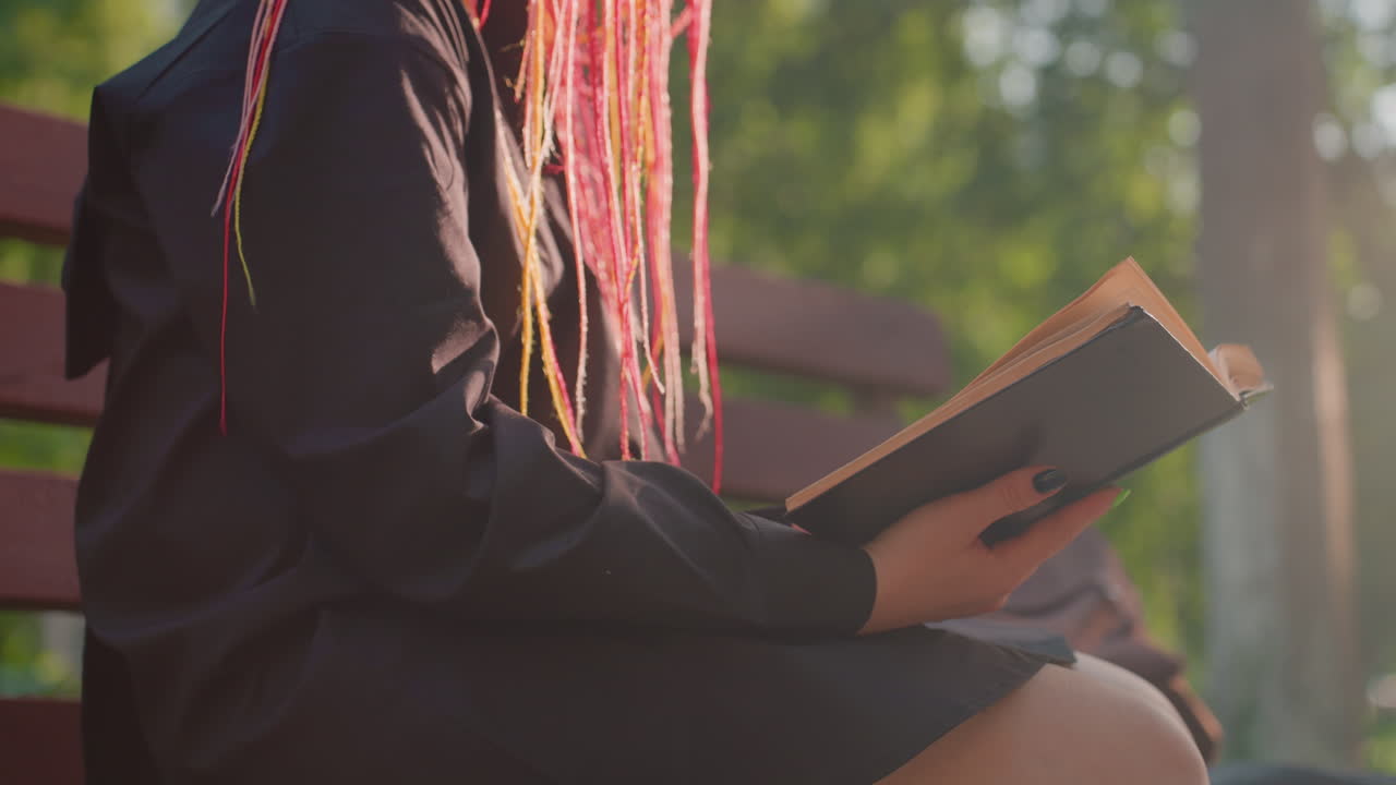 Ragazza con colorate trecce che legge un libro su una panchina in un parco soleggiato, mani che sfogliano le pagine e copertina vintage visibile; tranquillo momento da studentessa con trecce in stile indie, postura rilassata, alberi sullo sfondo dai colori tenui e atmosfera lenta