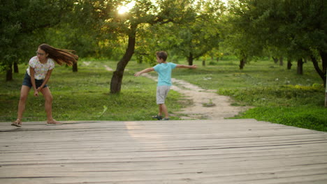 Two-brothers-and-sister-walking-in-park.-Kids-playing-with-frisbee-outdoors