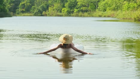 수영복과  모자를 입은 여자가 호수, 강, 연못에서 부풀어올릴 수 있는 원과 함께 떠다니고 있습니다. 소녀는 파란 물을 가진 수영장에서 수영 반지에 휴식을 취합니다. 여행, 휴가, 주말, 휴일, 자연에서 휴식을 취하고, 휴식, 휴식