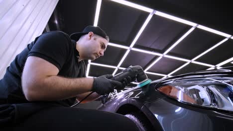 trabajador pulir un coche negro. detalle del coche - el hombre está usando maquinaria pulidores de automóviles mantenimiento para eliminar marcas reparación de acuerdo con la superficie de la pintura del coche antes de contin
