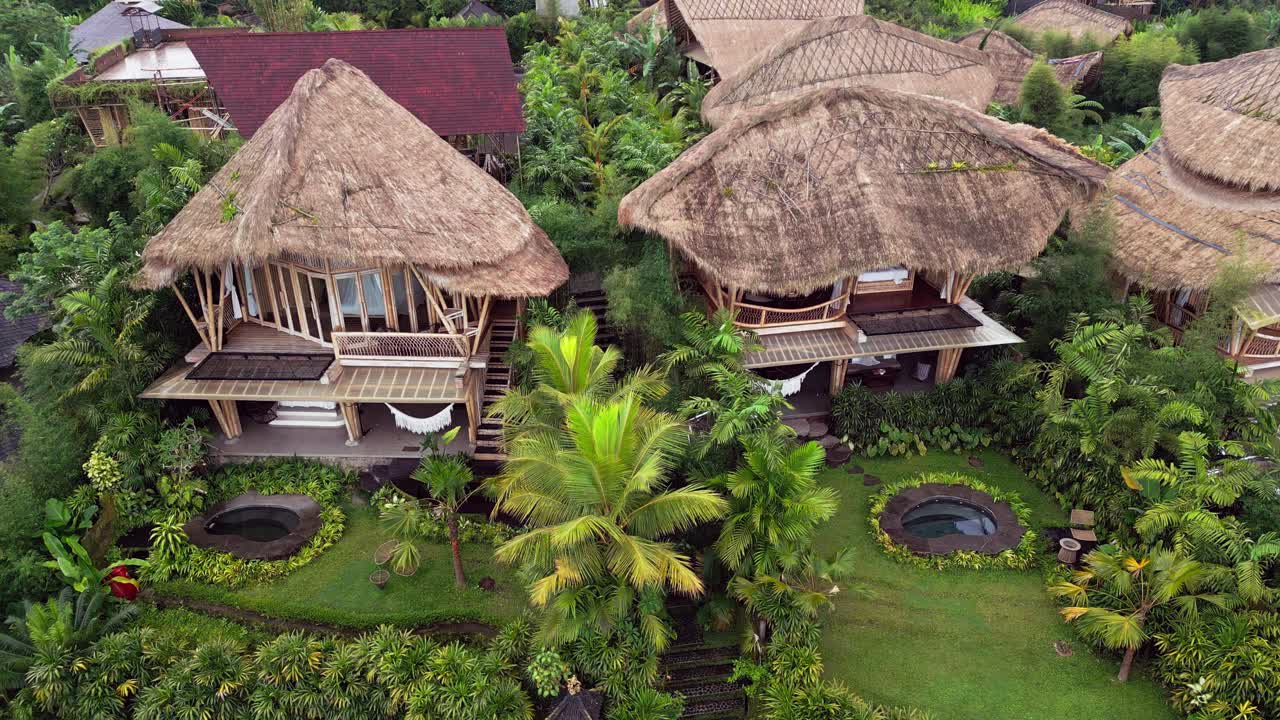 Stunning aerial footage of bamboo villas in Ubud, Bali, featuring thatched roofs, lush tropical gardens, private pools, and green surroundings that create a calm and eco-luxury escape