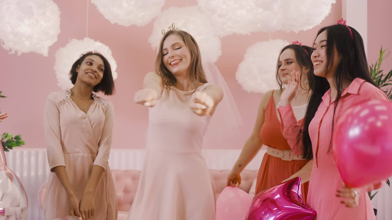 그녀의 친구들과 함께 카메라 앞에서 머리 장식과 베일 춤을 추는 행복한 총각 소녀의 전면 모습 1