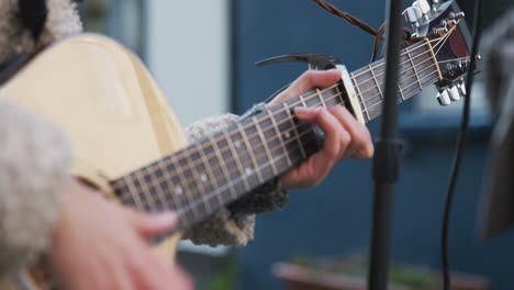 close up of female musician busking playing acoustic guitar outdoors in street