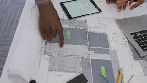 manos de arquitectos biraciales masculinos y femeninos usando tabletas y revisando los planes de los arquitectos en la oficina