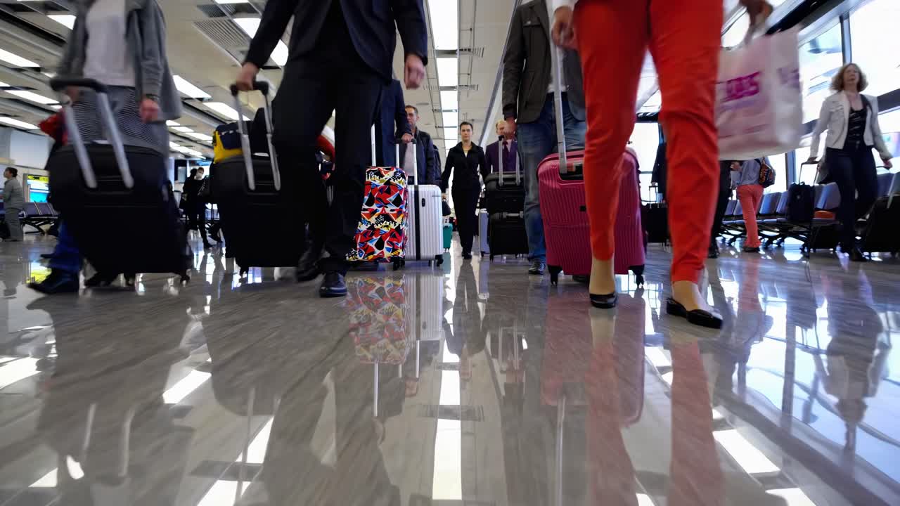Low-angle video shot capturing busy airport terminal, focusing on travelers' reflections