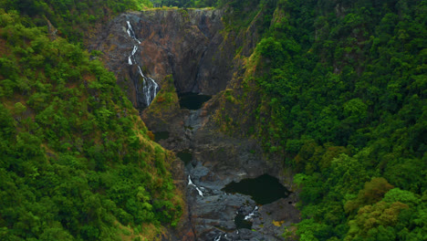 steep rocky mountains with flowing river in tropical rainforest in kuranda, cairns, qld australia