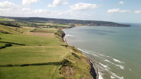 Aerial-of-North-Yorkshire-coastline-near-Ravenscar-with-green-fields-and-ocean