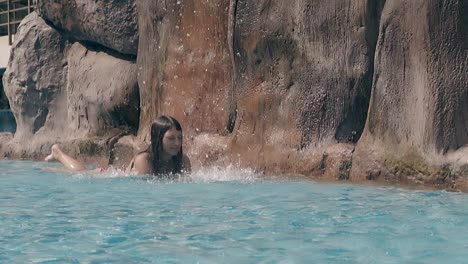 Glückliche-Frau-Liegt-Im-Flachen-Pool-Mit-Wasserfall-Zeitlupe