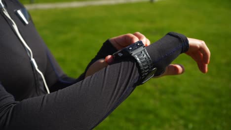 Cropped-shot-of-sportswoman-using-smartwatch-in-park