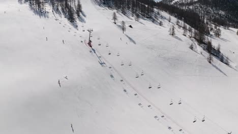 skiers skiing the slope in winter aerial view captured by drone