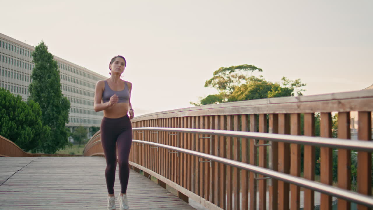 Motivated athlete running morning bridge. Woman doing cardio training jogging