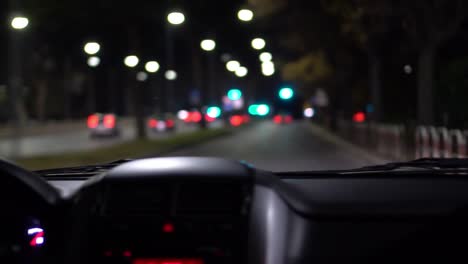 night ride in a car with bokeh car lights and street lamp, car dashboard in the foreground.