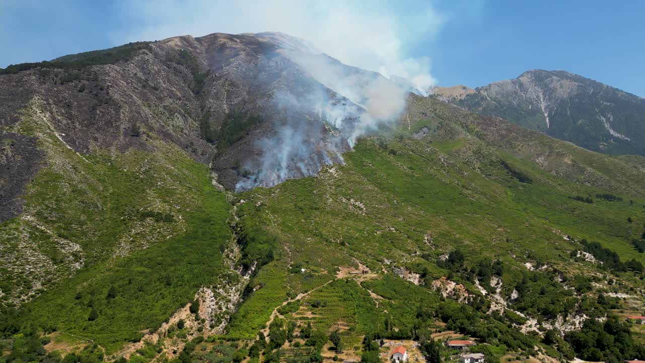 Wildfires burning on the side of the mountain and closing in on the village and houses and the foot of the mountain