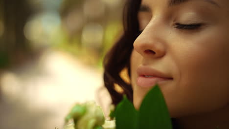 Affectionate-woman-smelling-flowers-in-park.-Lady-holding-rose-bouquet-outdoors