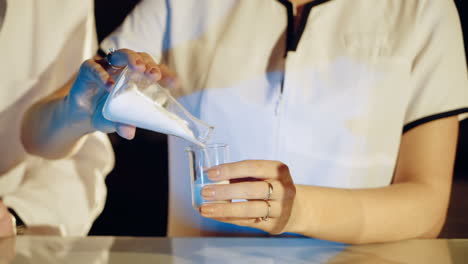 experiments in a chemistry lab. young woman scientist mixing reagents from glass flasks