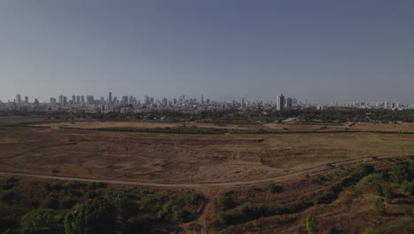 aerial slide to the left over uncultivated agricultural land, the city of tel aviv in the distance