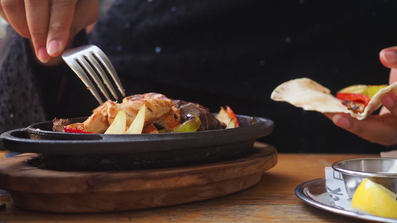 Persona comiendo fajitas con tortilla en un restaurante