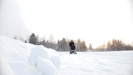 Statische-Zeitlupenaufnahme-Eines-Vaters,-Der-Mit-Einem-Kinderwagen-Im-Verschneiten-Wintersturm-Spazieren-Geht