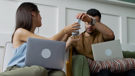 student talking with female mate sitting on sofa while looking at laptop 2