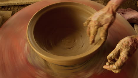 An-Asian-woman-finishes-a-new-bowl-on-a-manual,-foot-powered-turning-table,-showcasing-the-beauty-of-pottery-as-a-craft