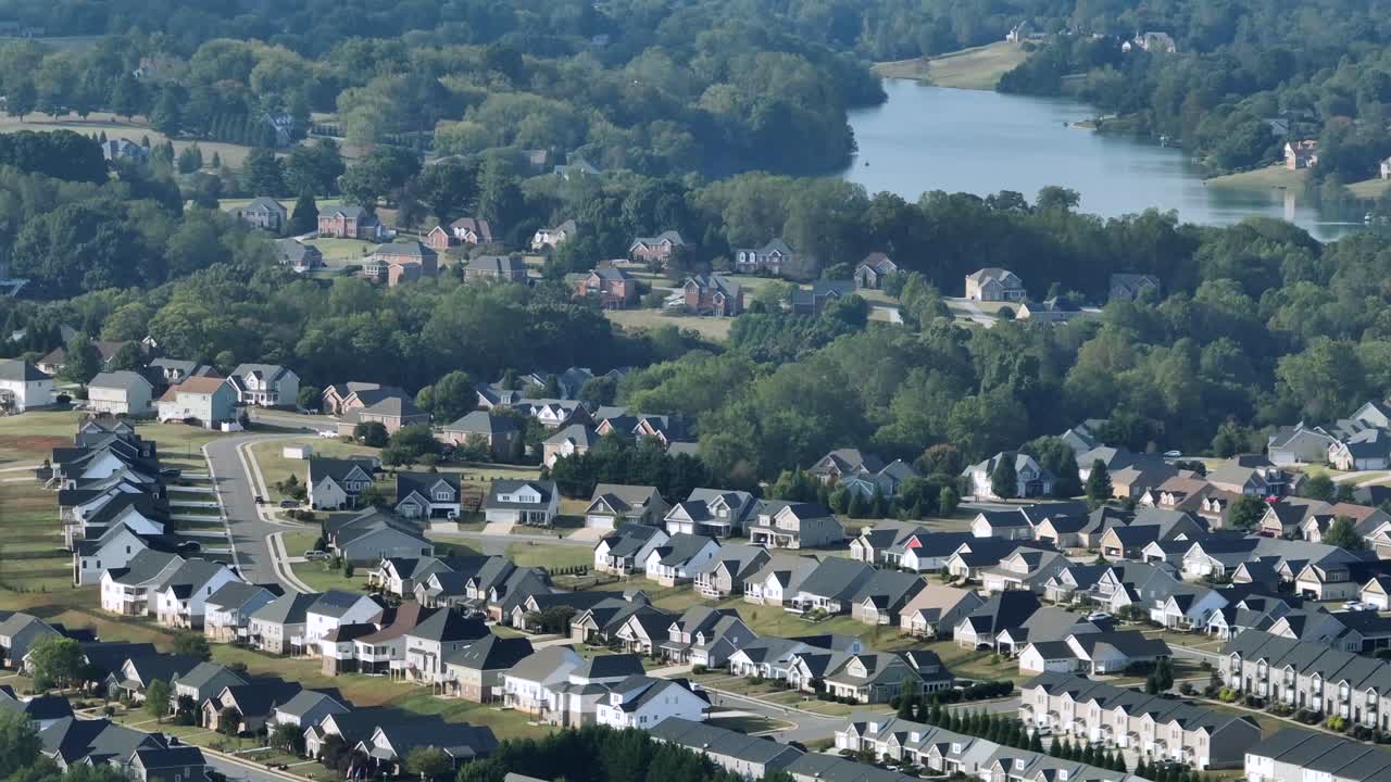 Række af moderne huse til en familie med hvide facader og sorte tage i en stille forstad. Bredt luftfoto. Amerikansk forstad med sø i det fjerne. Solrig sommerdag i et skovområde