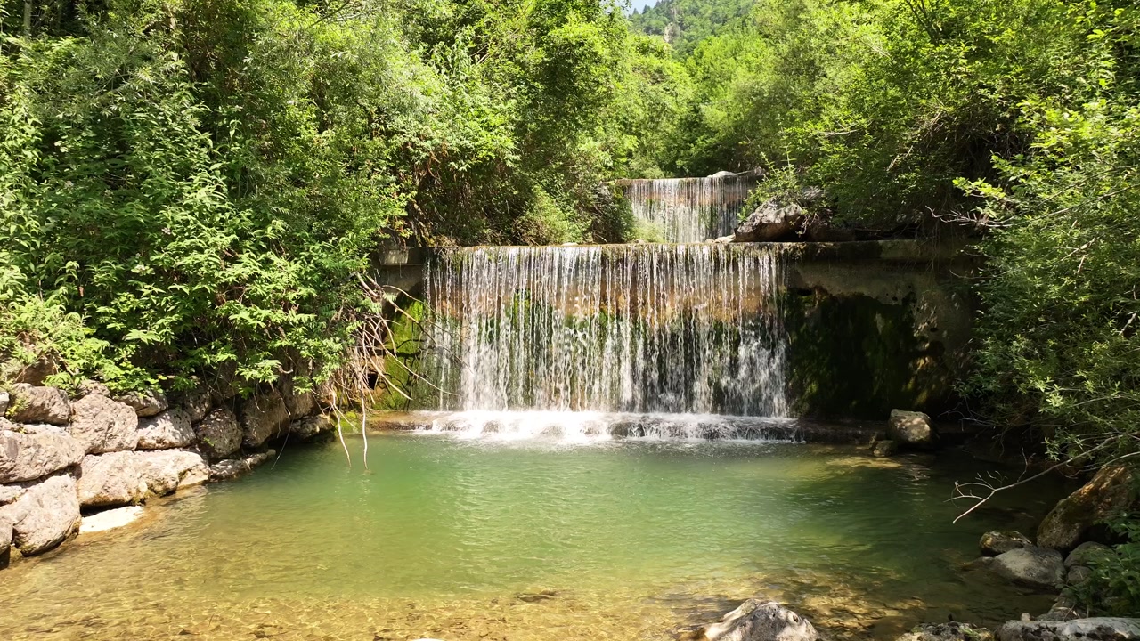 Tranquil waterfall cascade with lush forest and clear pool in Switzerland