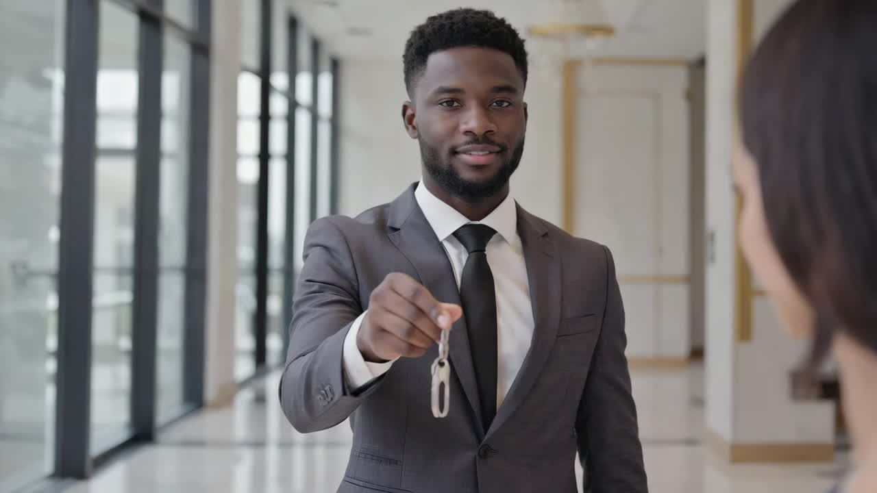 Professional man in suit handing over keys to a woman