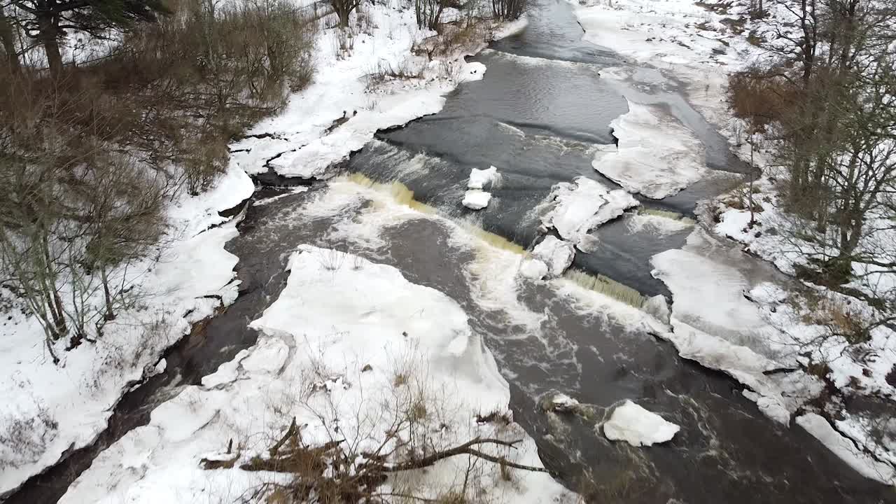 눈 덮인 풍경 사이에서 겨울 동안 흐르는 강의 공중 드론 보기