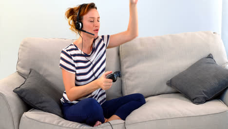 mujer con auriculares jugando un juego de joystick en el sofá 4k
