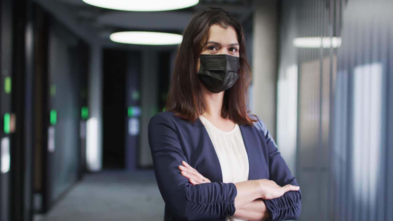 retrato de una mujer de negocios caucásica con cabello marrón con máscara facial en una oficina moderna