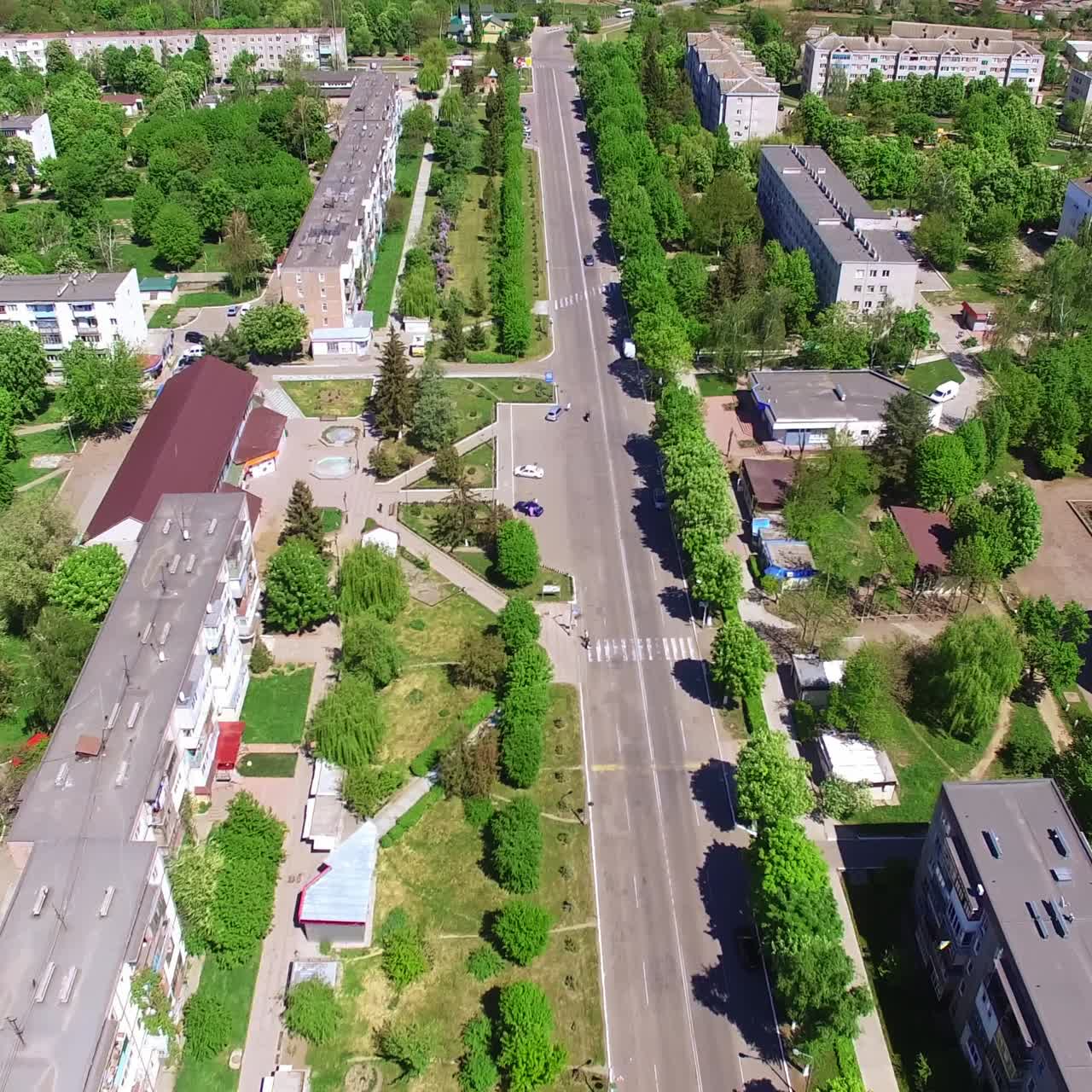 Strada rettilinea che attraversa una tipica città di provincia. Filmato aereo con drone sopra il quartiere residenziale ricco di alberi e parchi