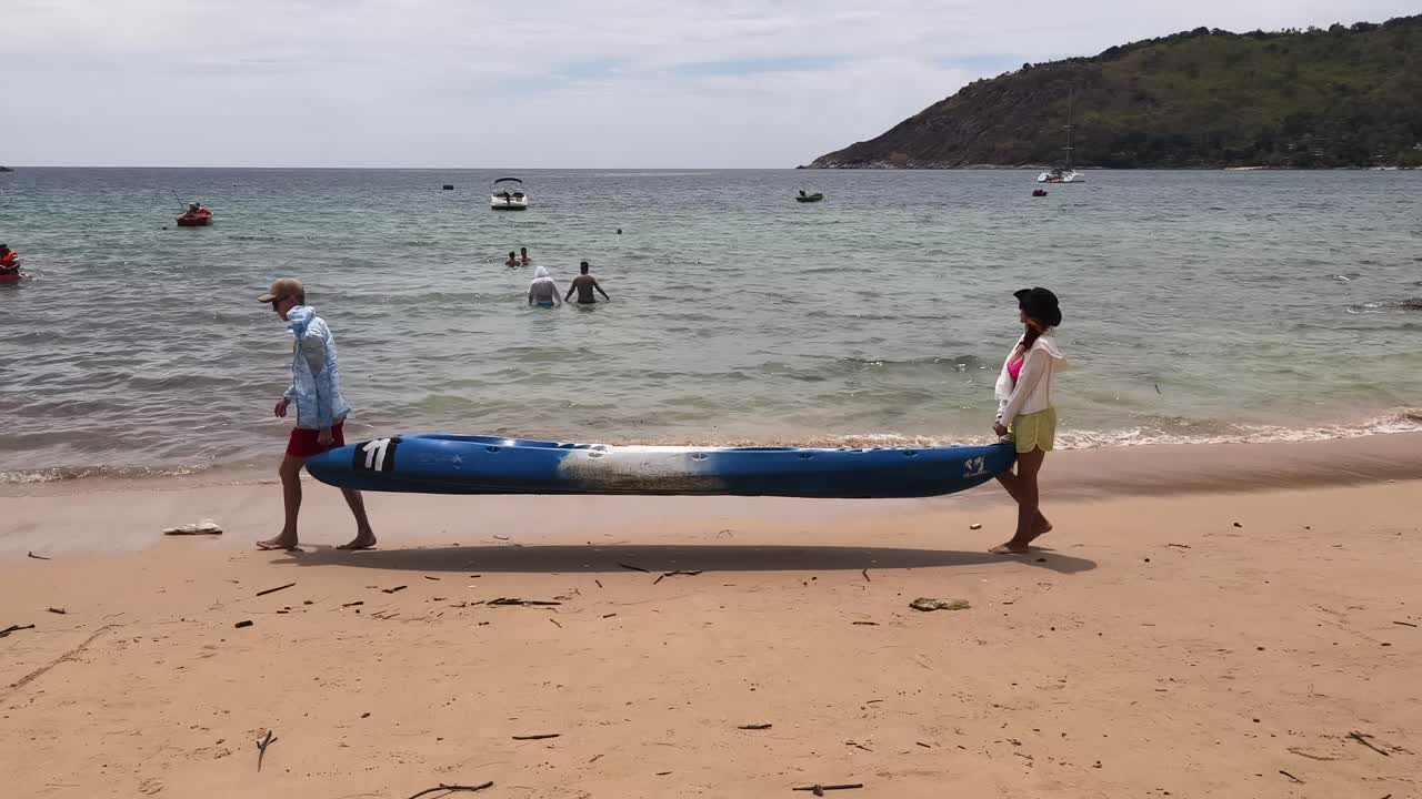 Couple Carrying Kayak on Beach