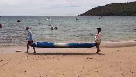 couple carrying kayak on beach