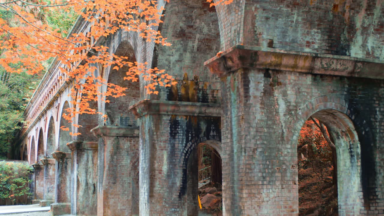 일본 교토의 벽돌 다리 주변의 아름다운 오렌지색 잎 부드러운 조명