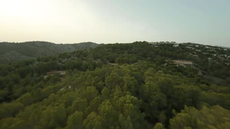 aerial drone forward moving shot downhill the green mountain range at daytime cala d'egos beach mallorca, spain