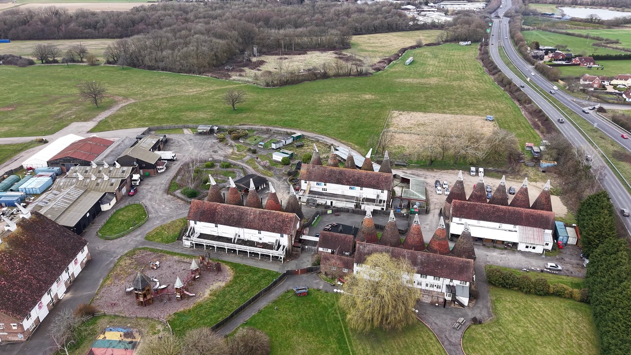 Hop farm in Tonbridge Kent aerial view flying across British A road towards rustic oast houses