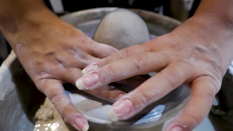 overhead close view of an african american hands spinning clay and setting the wet mold on the wheel very carefully