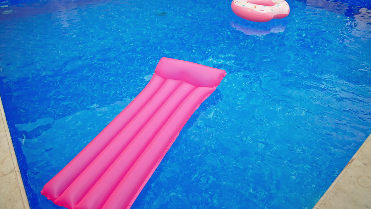 Swimming circle and inflatable mattress on the water surface. Swimming appliances in the pool with no people in. View from top.