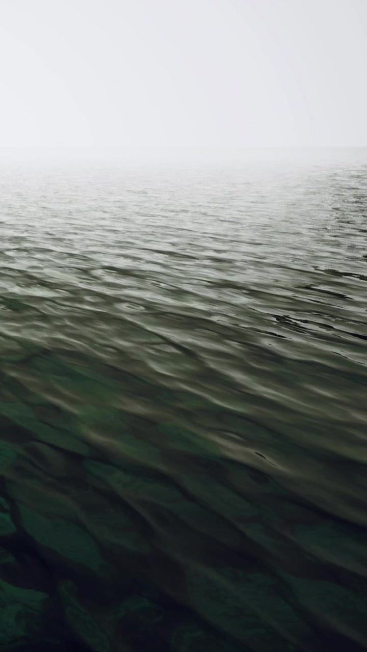 Waves move gently on the surface of the water during morning fog